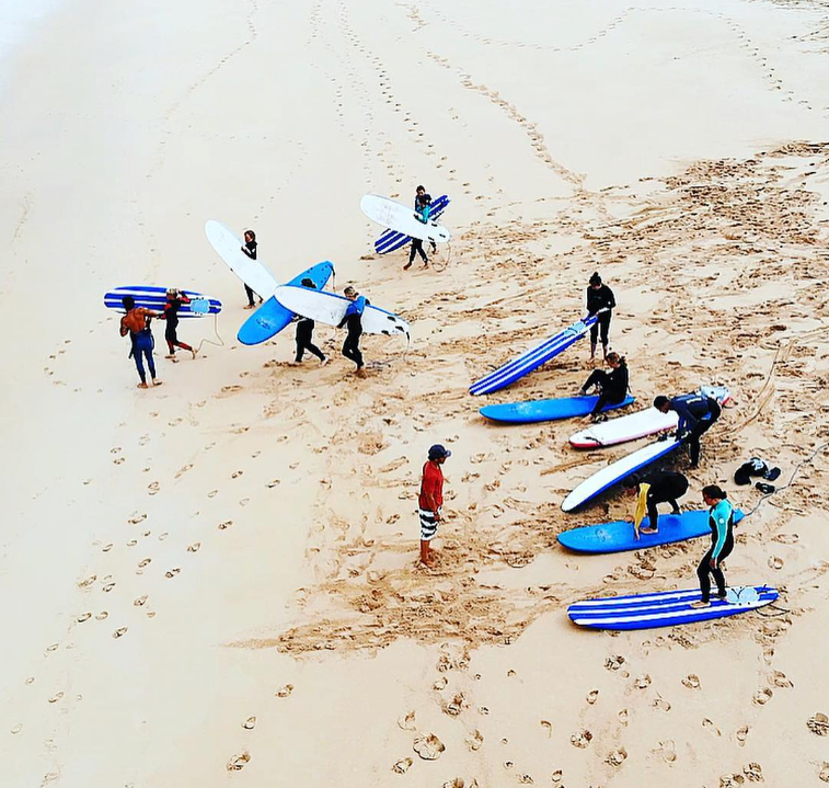 A group of people carrying surfboards on a sandy beach
