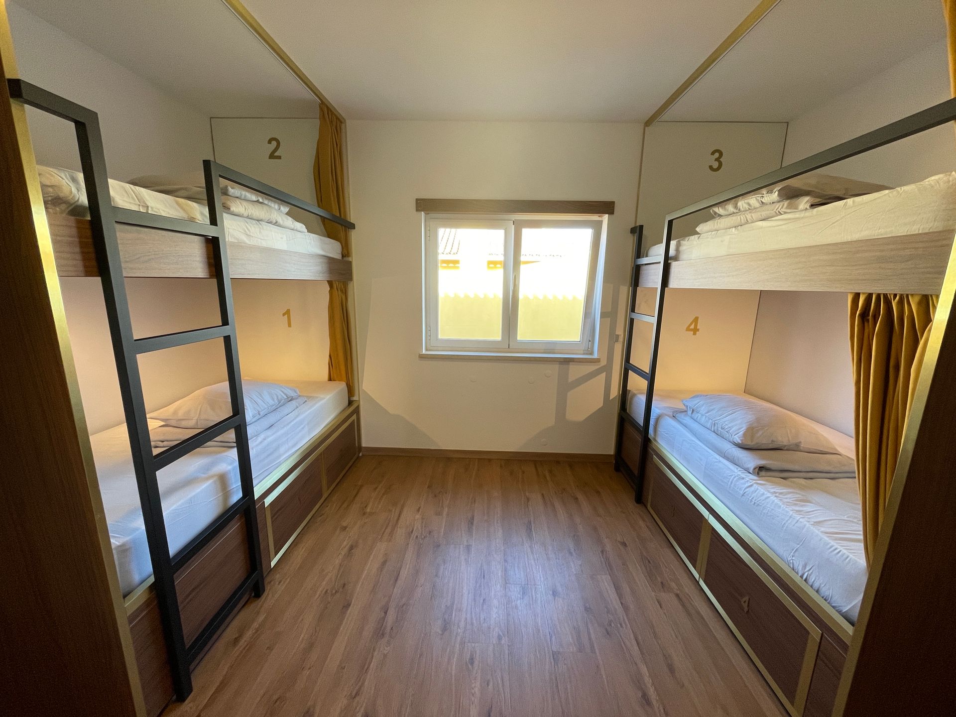 A bunk bed room with four bunk beds and a window.