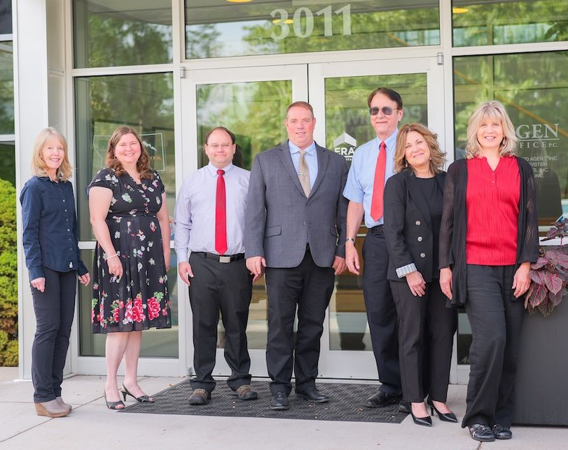 Group of seven people standing in front of a building with glass doors and the number 3011.