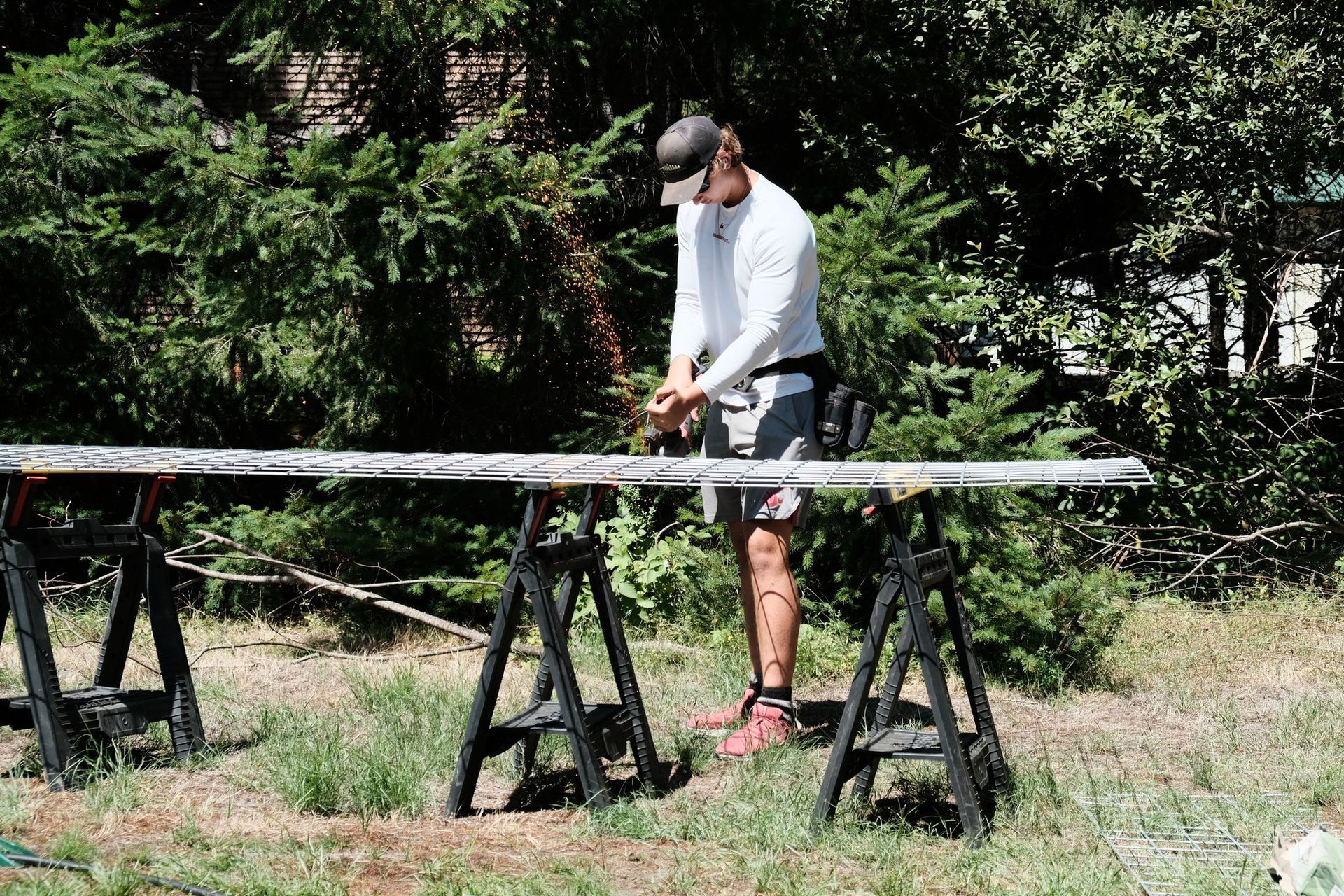 A man is cutting a piece of wood with a saw in a field.