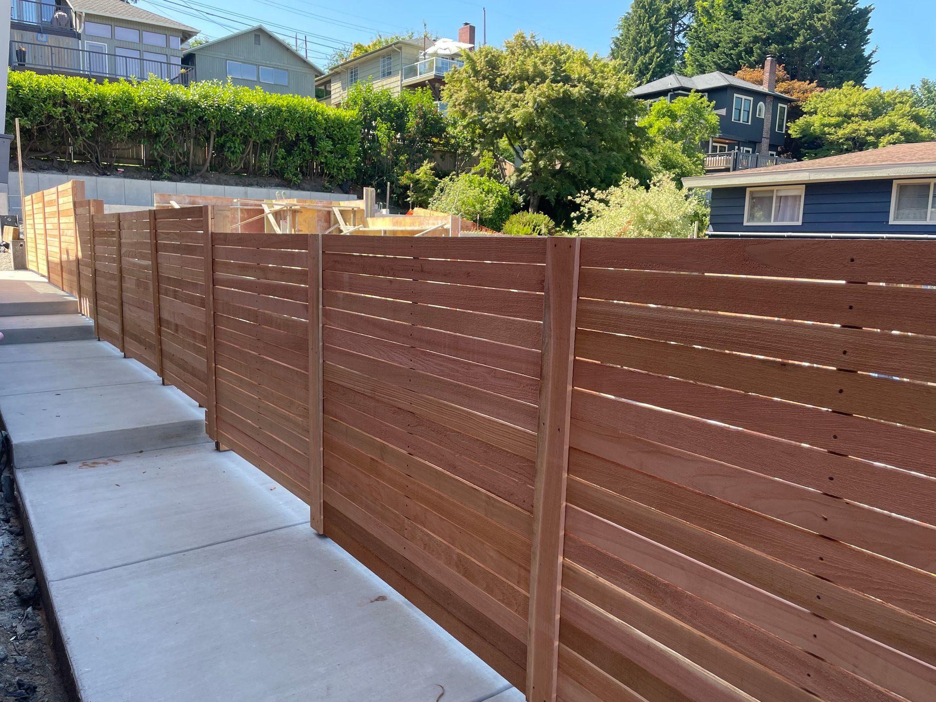 A wooden fence is surrounded by a stone wall and grass.