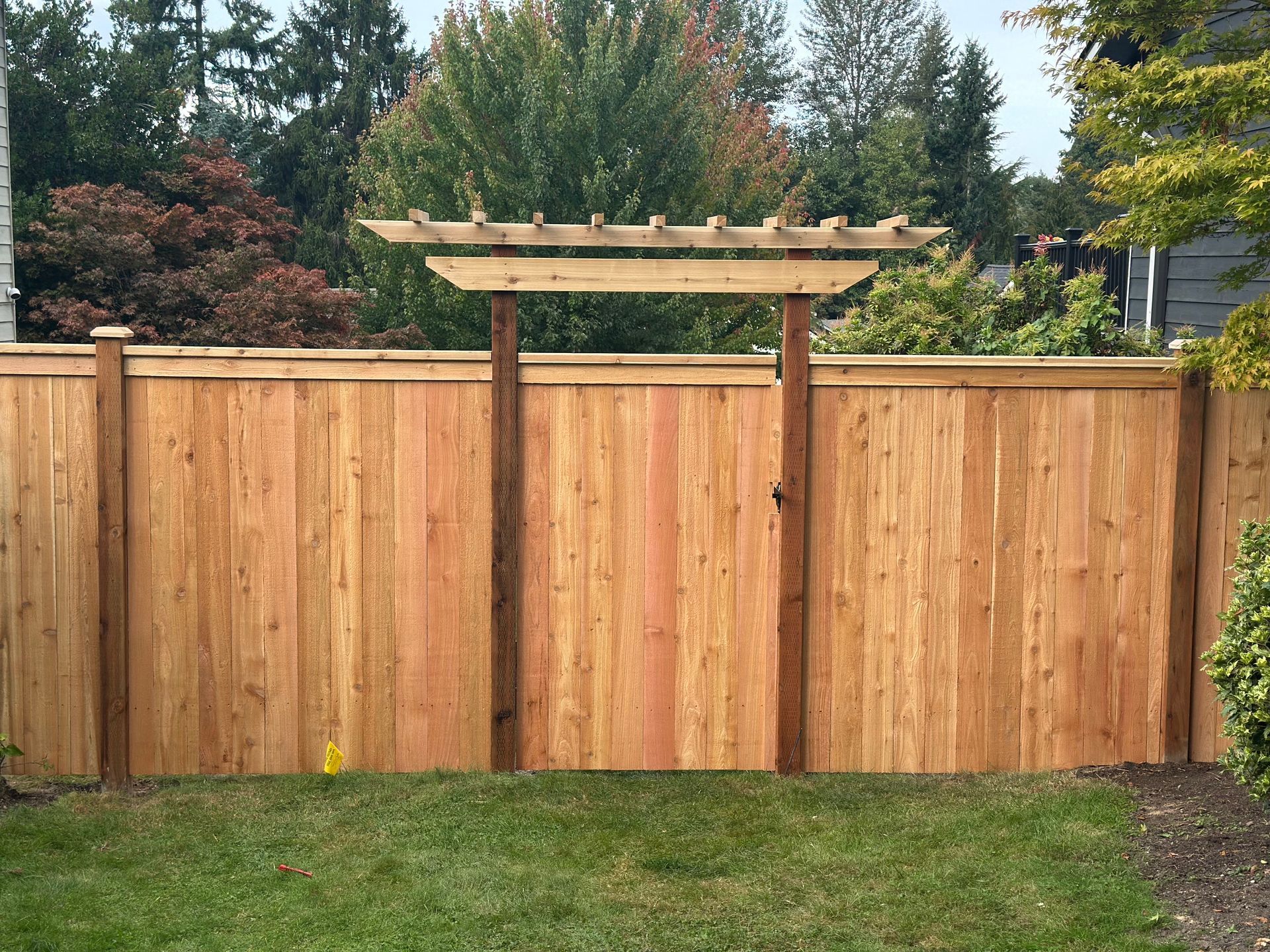 A wooden fence is in the backyard of a house.
