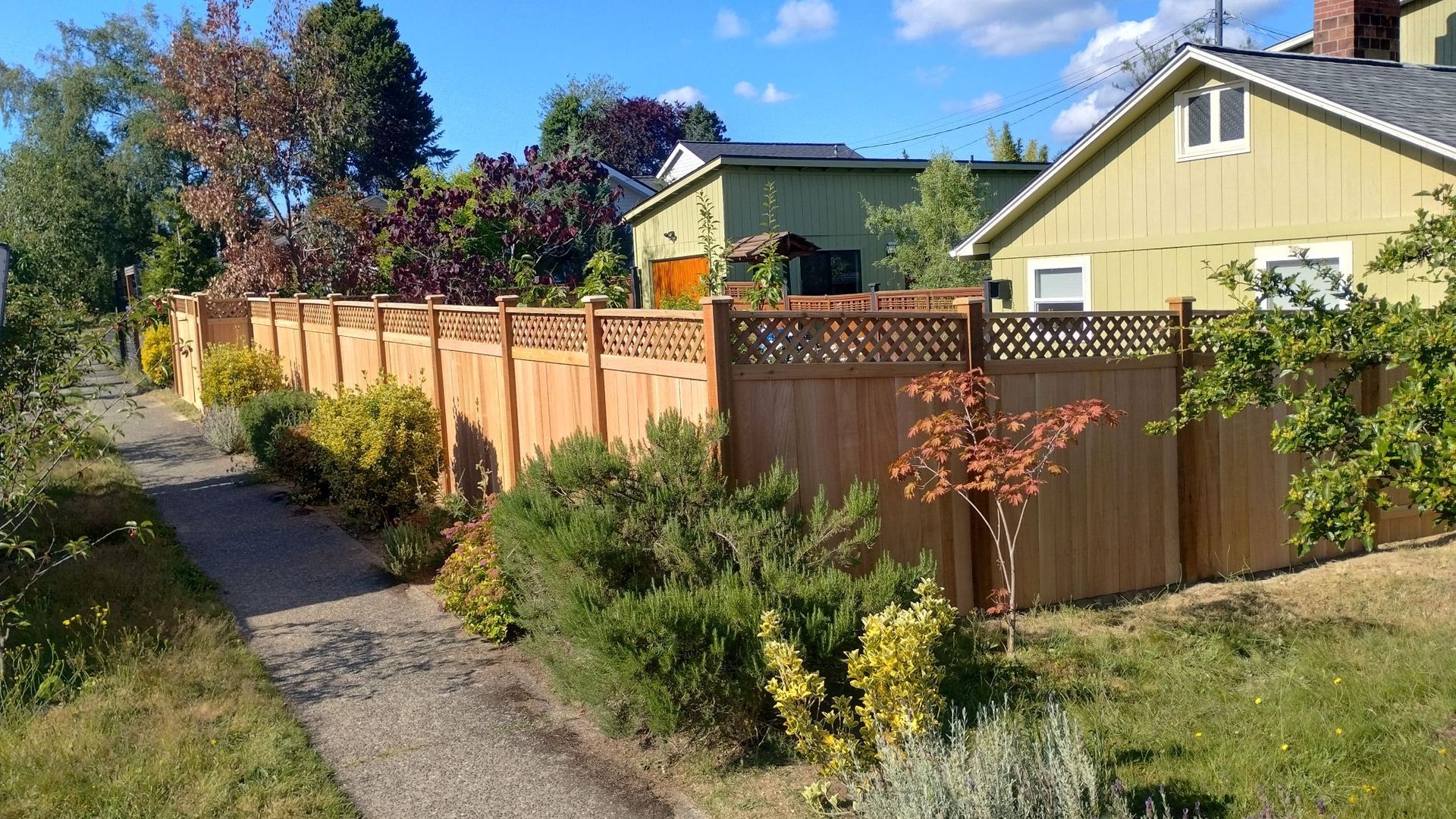 A wooden fence is surrounded by snow in front of a house.