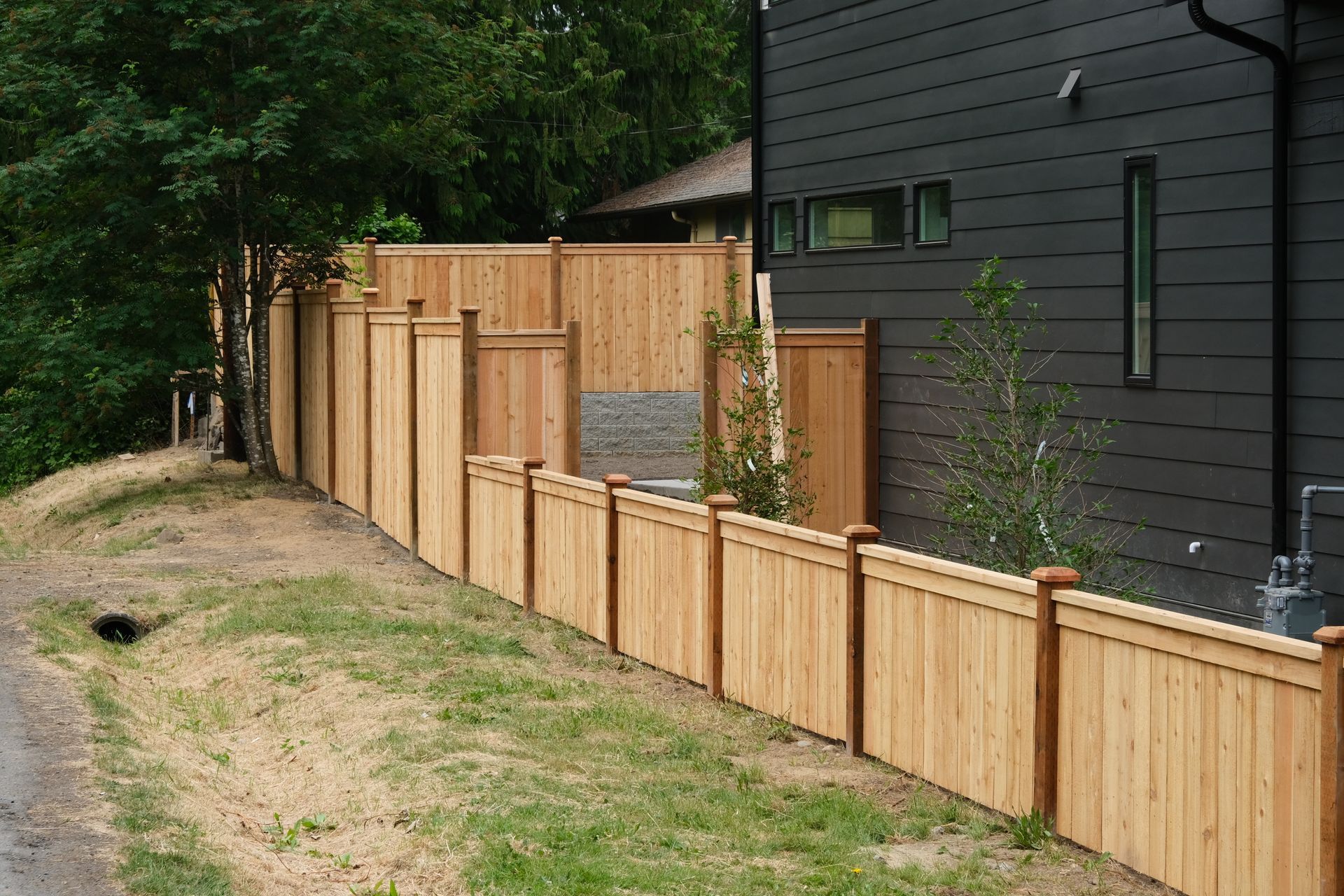 A wooden fence in front of a house with snow on the ground.