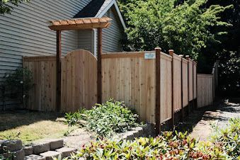 Wooden fence with a gate and pergola next to a house, outdoor.