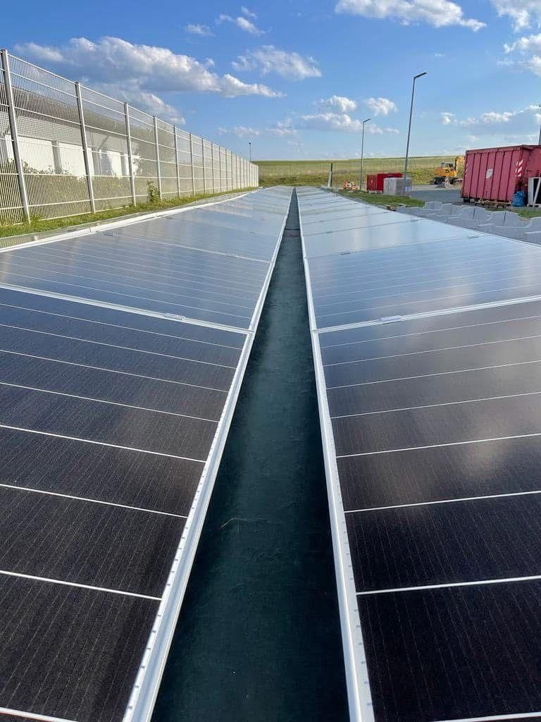 A row of solar panels are sitting next to each other in a field.