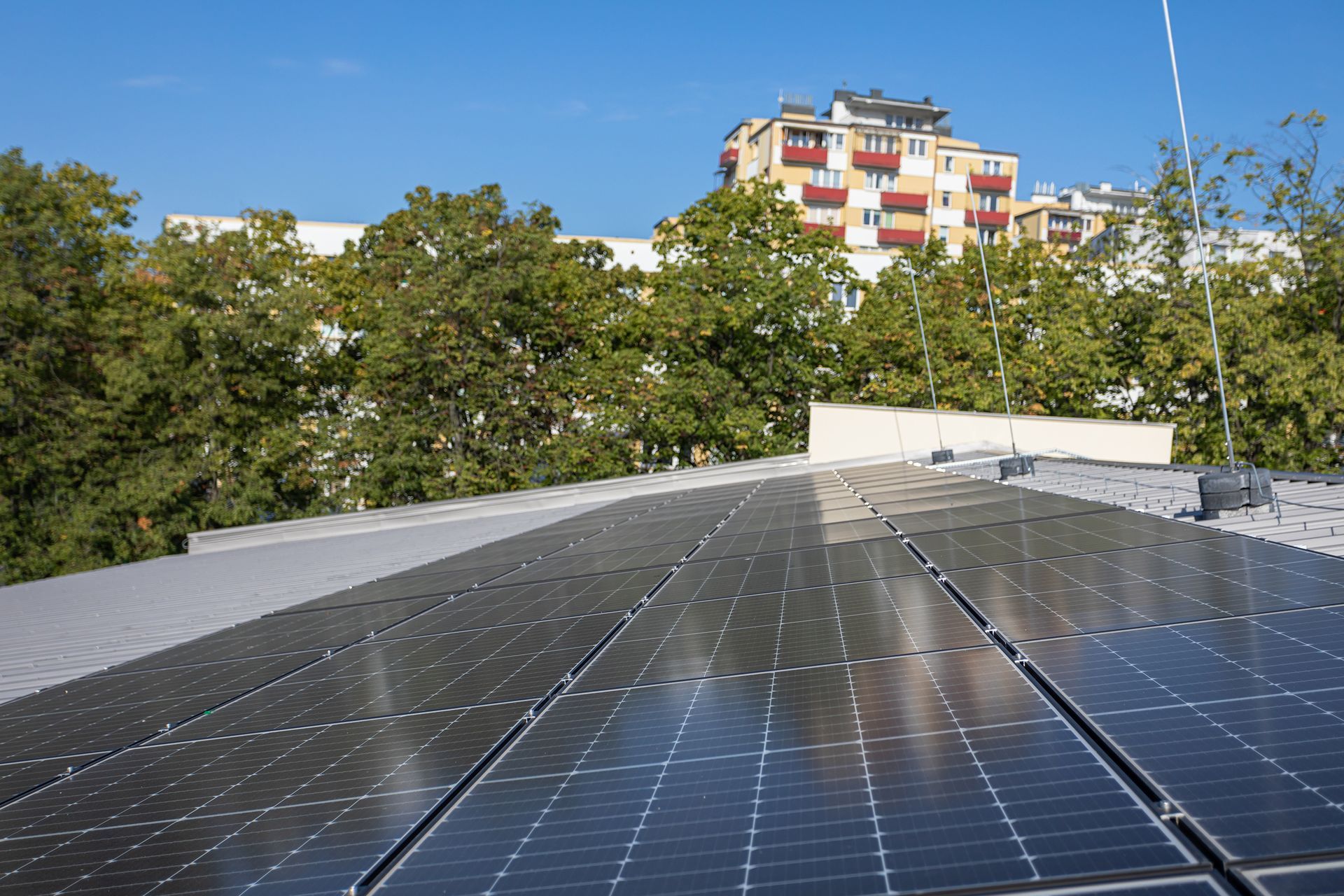 There are many solar panels on the roof of a building.
