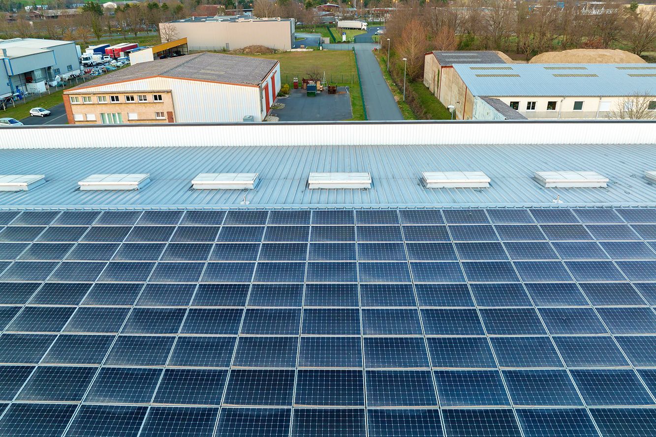 Two men are installing solar panels on the roof of a building