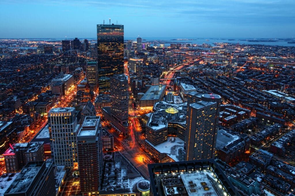 City skyline at dusk with lights, snow, and tall buildings.