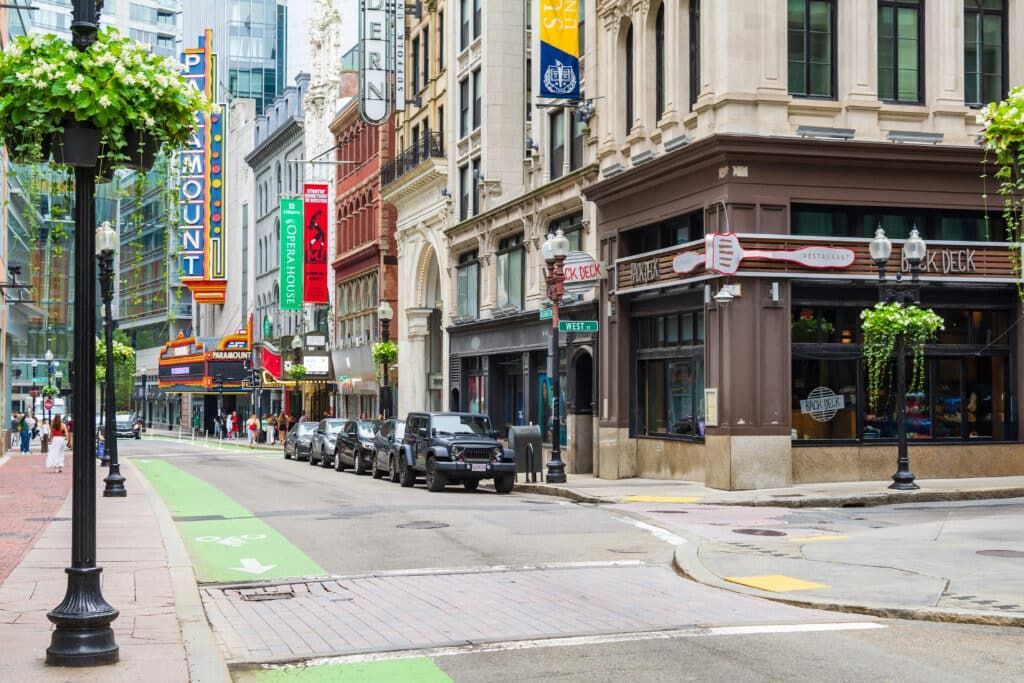 Street scene with buildings, parked cars, and a bike lane in a city.