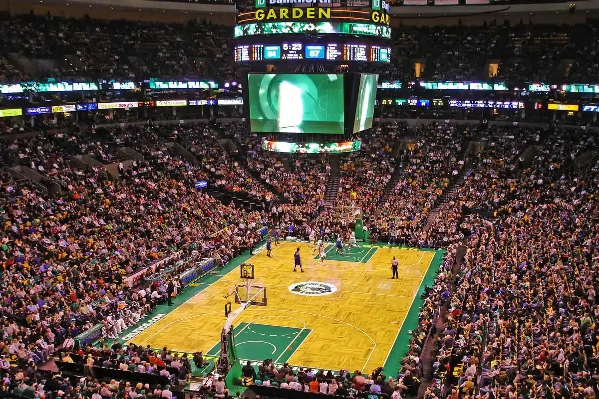 Basketball game at TD Garden, Boston. Court with players, packed stands, and scoreboard.