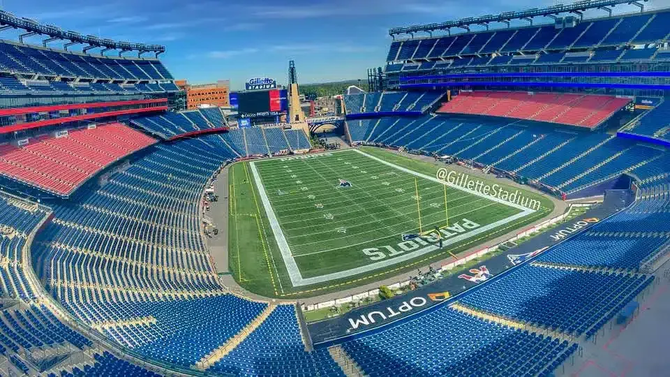 Empty football field at Gillette Stadium with blue and red seating.