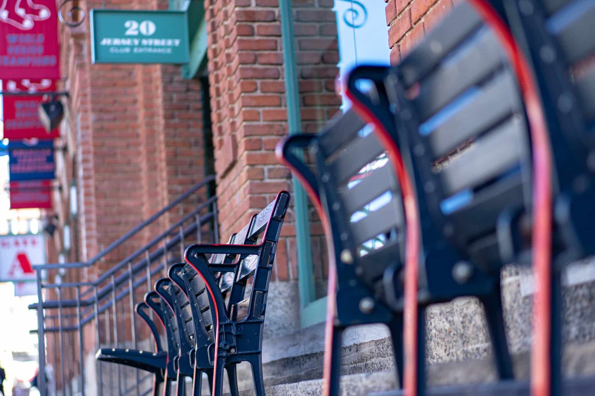 Row of black benches with red accents along a brick building, sign that says 20 Jersey Street.
