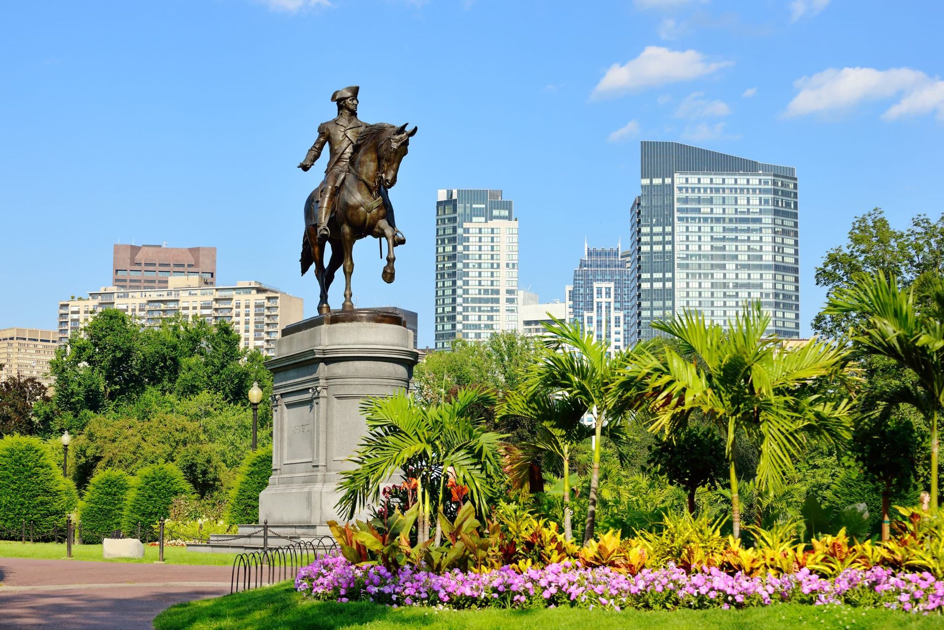 Bronze statue of George Washington on horseback in Boston's Public Garden, with city buildings in the background.