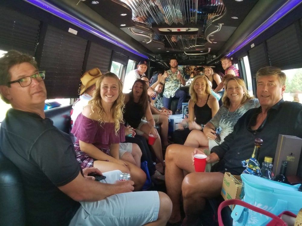 Group of people enjoying themselves inside a party bus. They are smiling, drinking, and laughing.