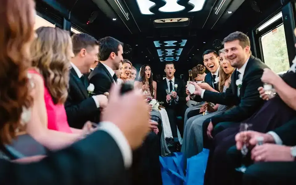 People celebrating in a limousine. Men in suits and women in dresses, champagne glasses held up, joyful expressions.