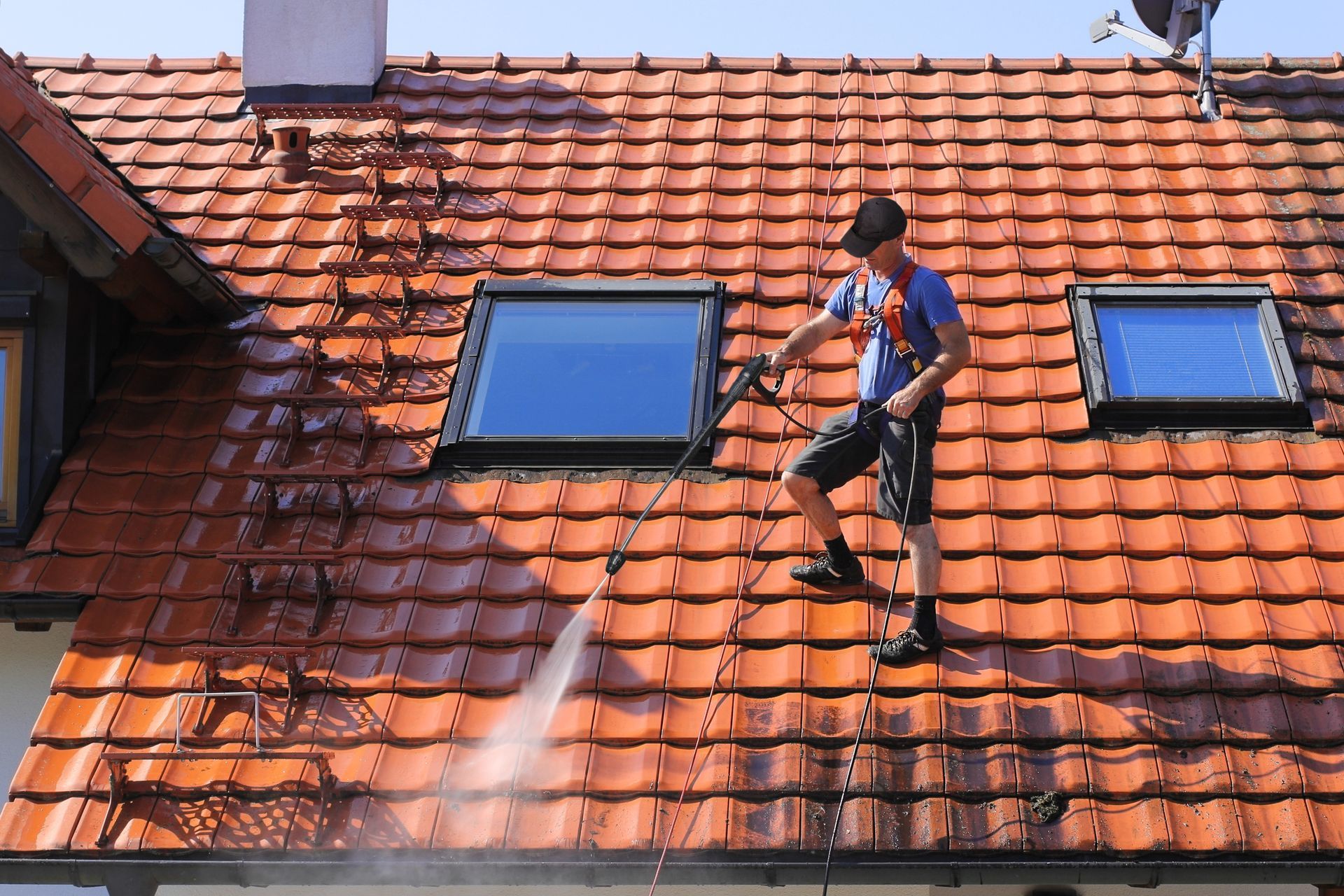A professional worker is cleaning the roof and gutters with high water pressure.
