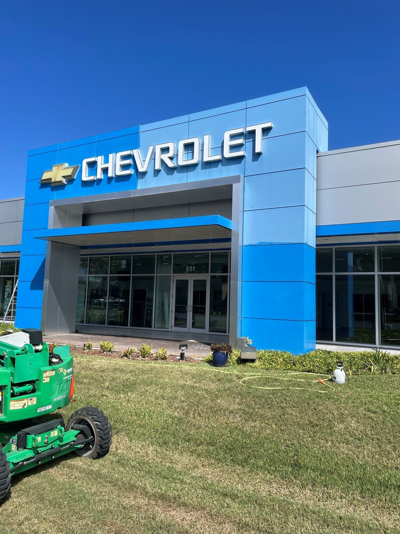 Chevrolet dealership building with blue accents, green grass, and a clear sky.