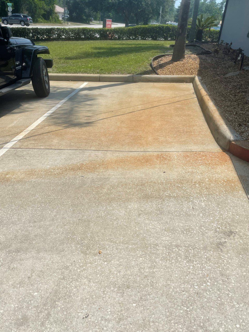 Concrete parking space with rust-colored stains; a black Jeep is parked to the left.
