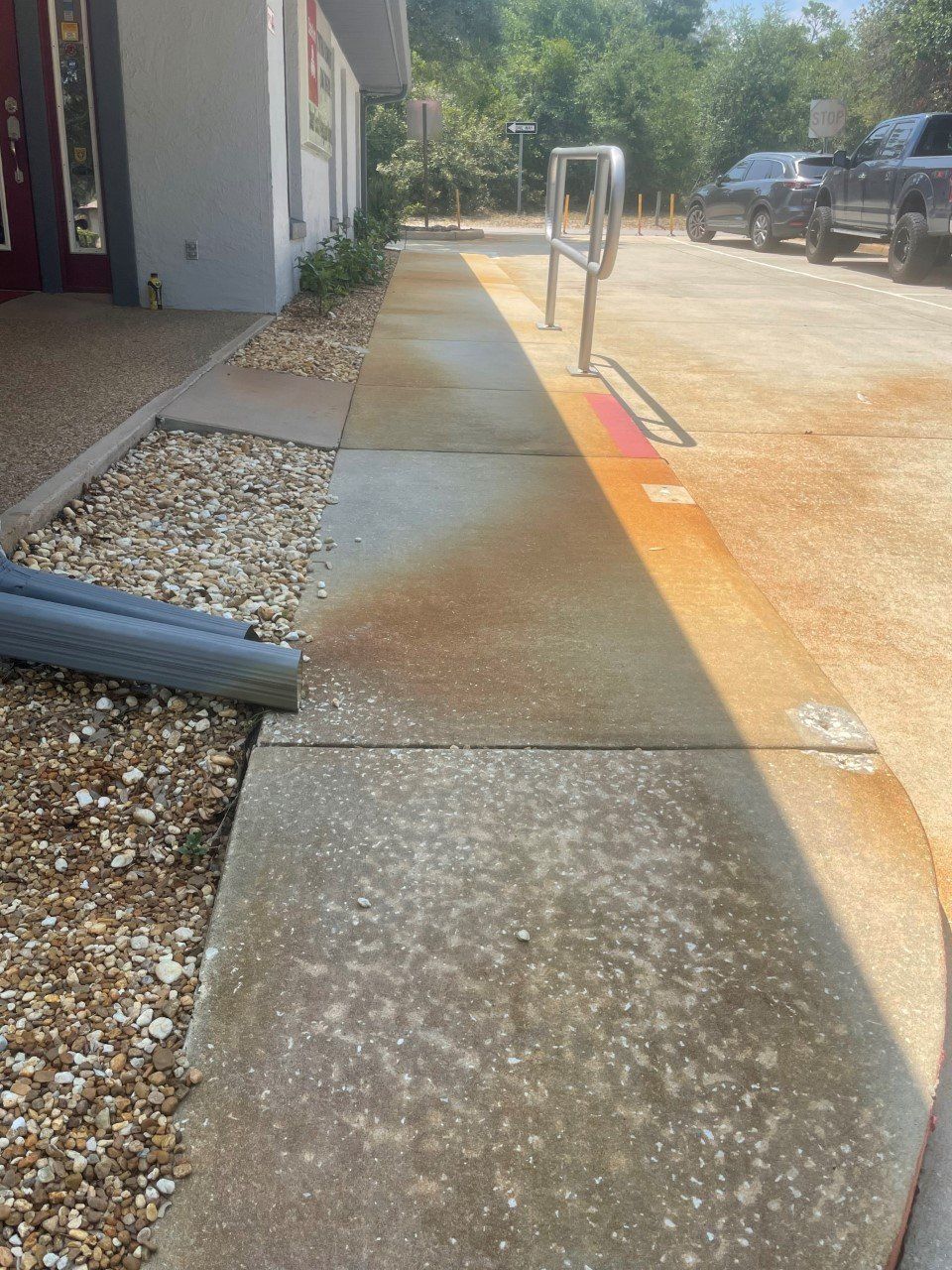 Concrete walkway with rust-colored staining next to a building and gravel.