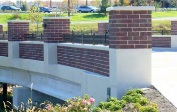 A bridge with brick pillars and flowers on the side of it.
