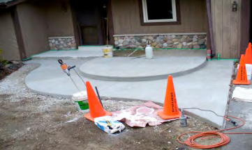 A concrete walkway is being built in front of a house.