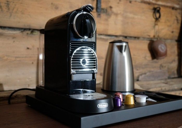 A nespresso machine is sitting on a tray next to a kettle.