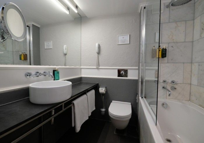 A bathroom with a sink , toilet , bathtub and mirror.