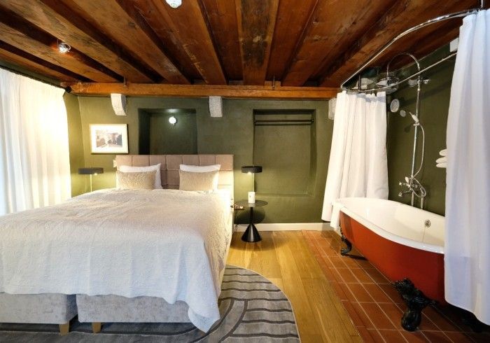 A bedroom with a large bed and a red bathtub
