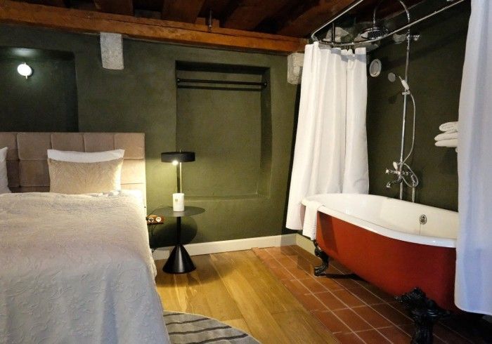 A bedroom with a red bathtub and a bed