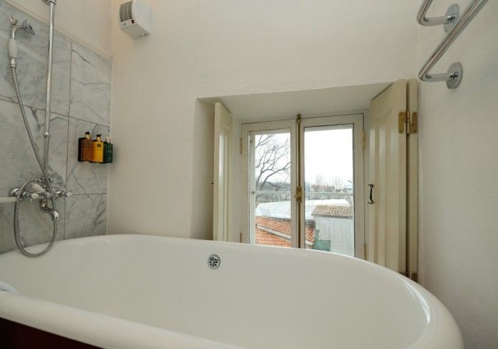 A bathtub in a bathroom next to a window