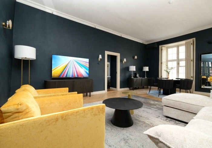 A living room with a yellow couch and a black coffee table
