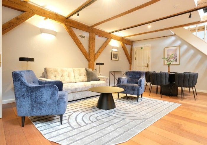 A living room with a couch , chairs , a table and a rug