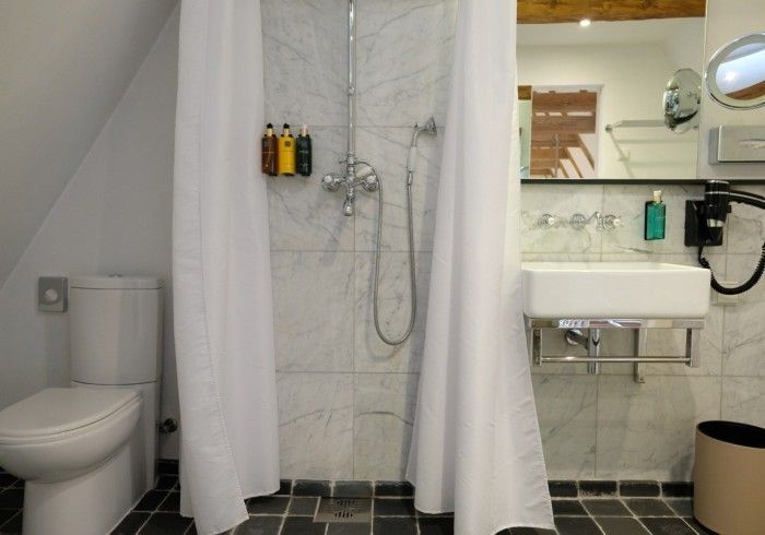 A bathroom with a toilet , sink , shower and mirror.