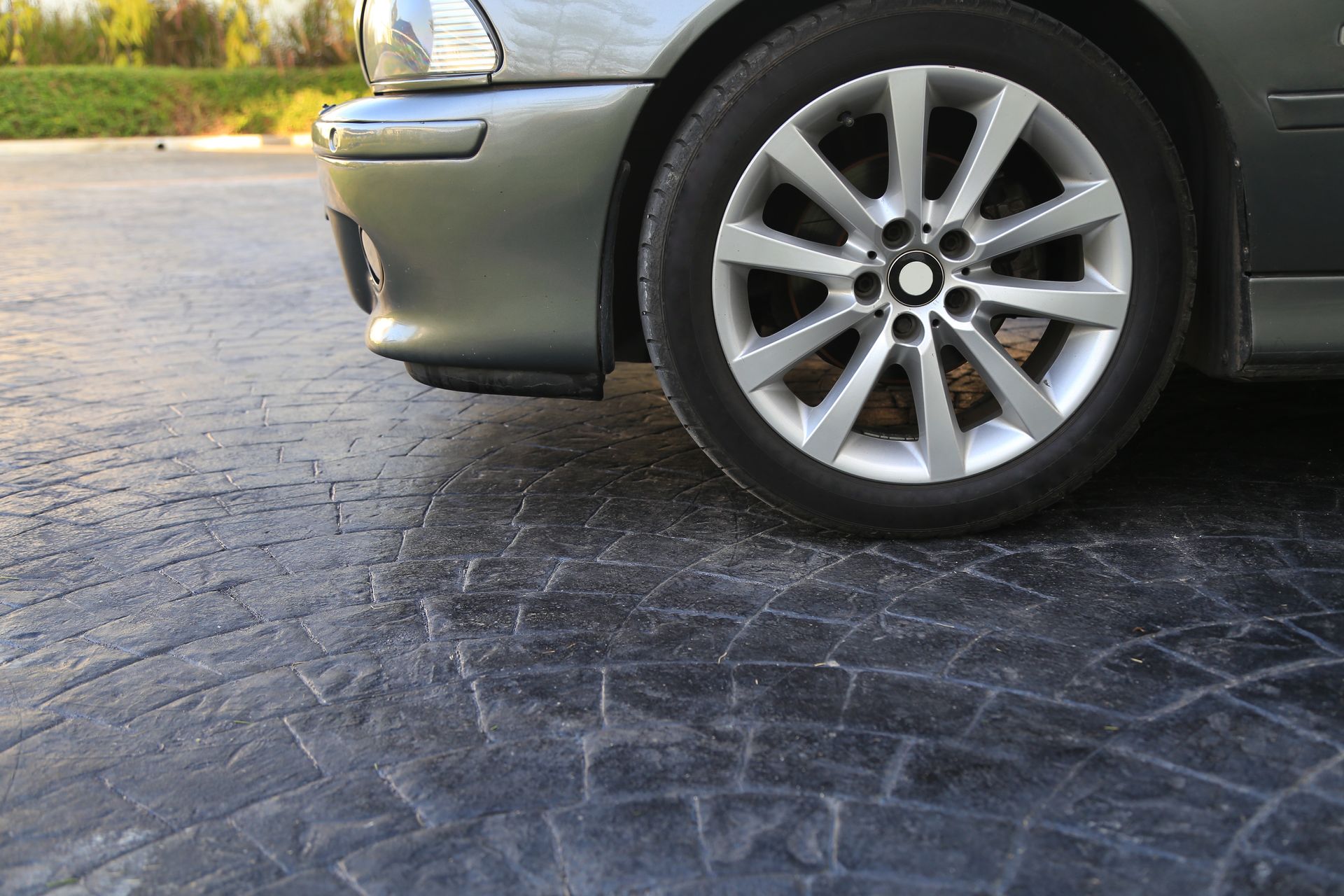 A car is parked on a cobblestone driveway.
