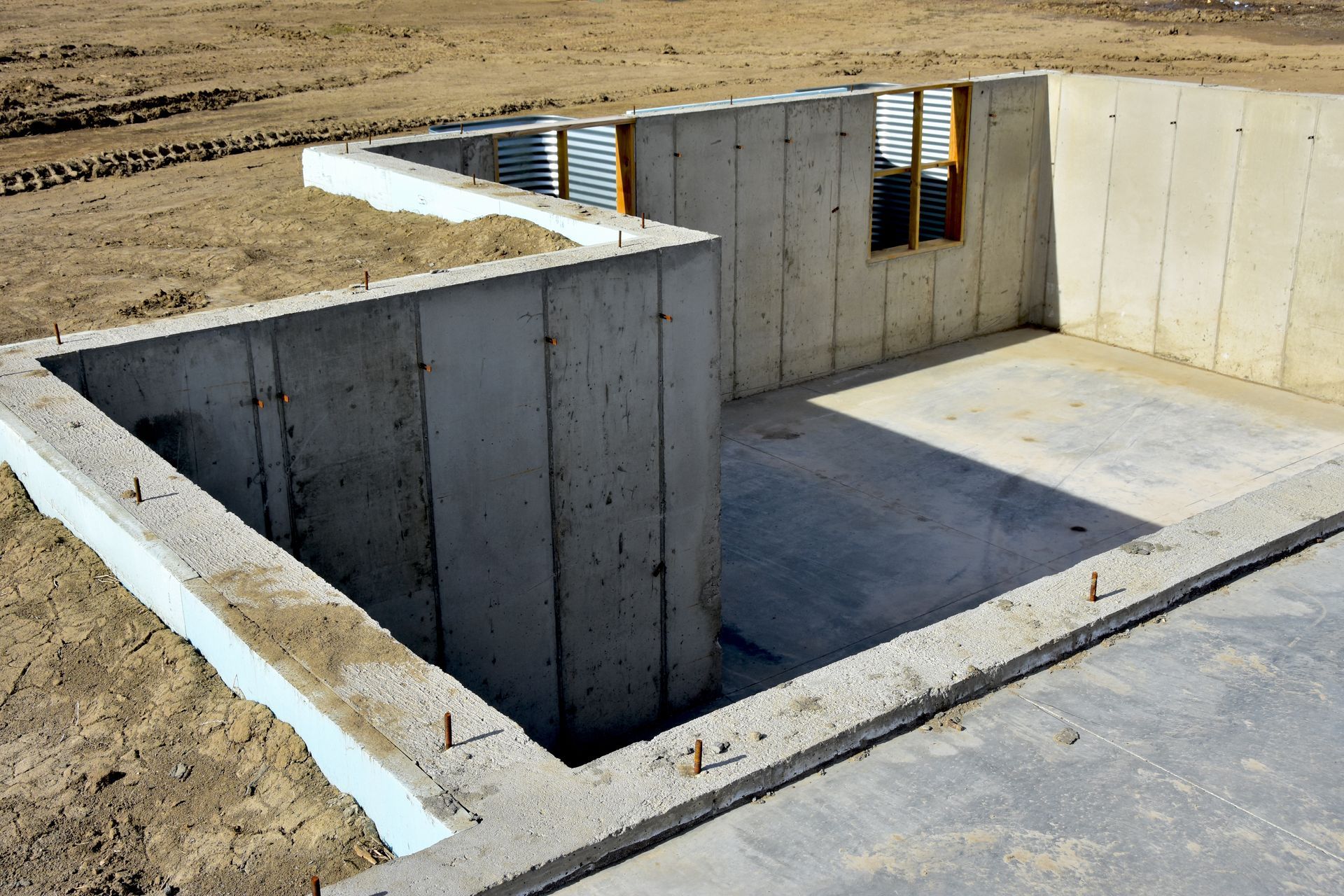 A concrete basement is being built in a dirt field.