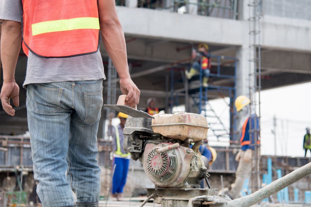 Construction Worker Walking With a Small Motor — Bampak In Gympie, QLD