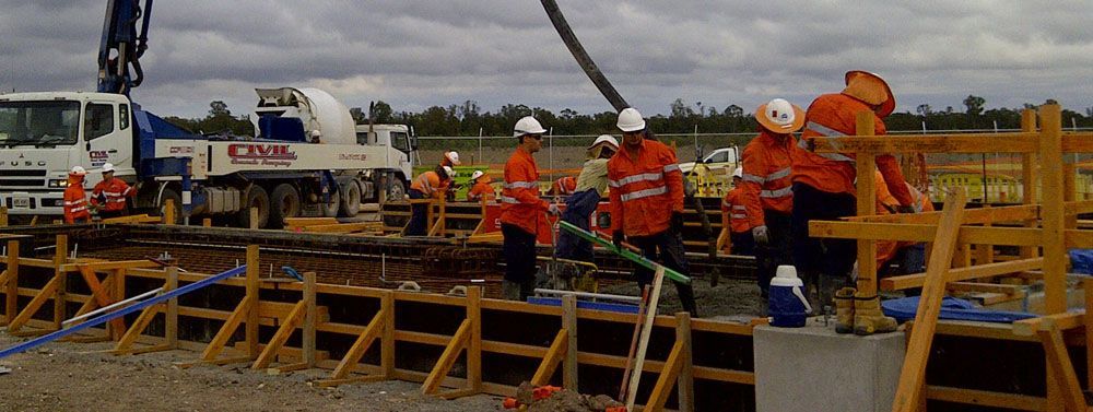 Professionals in Orange Uniform Pouring Concrete Cement — Bampak In Coolum Beach QLD