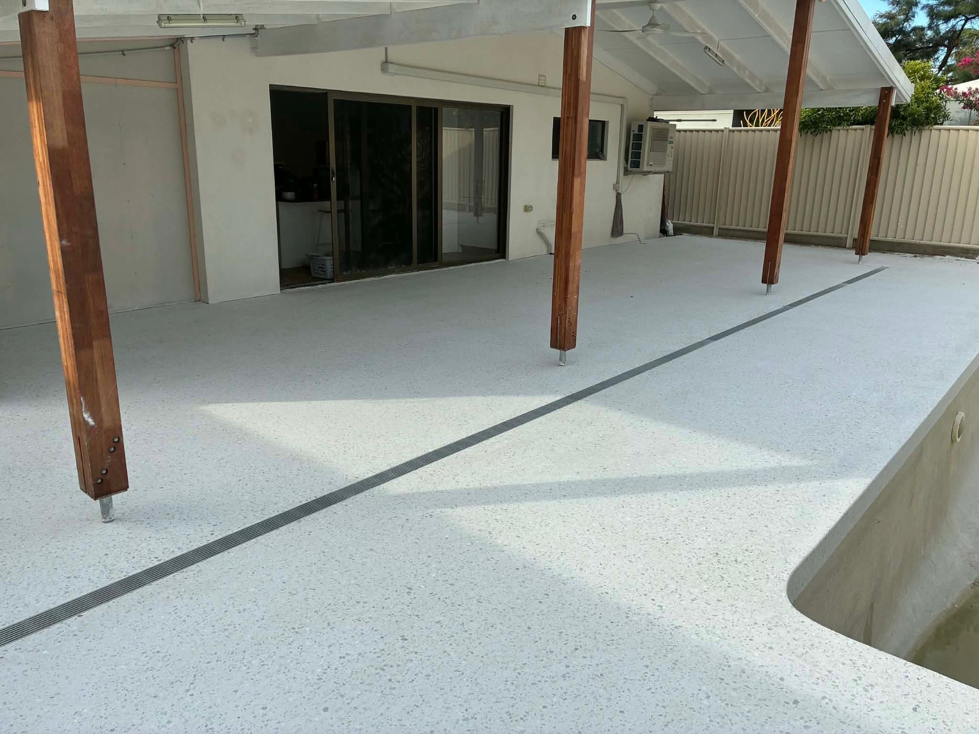 White speckled patio with wooden beams and a sliding glass door.