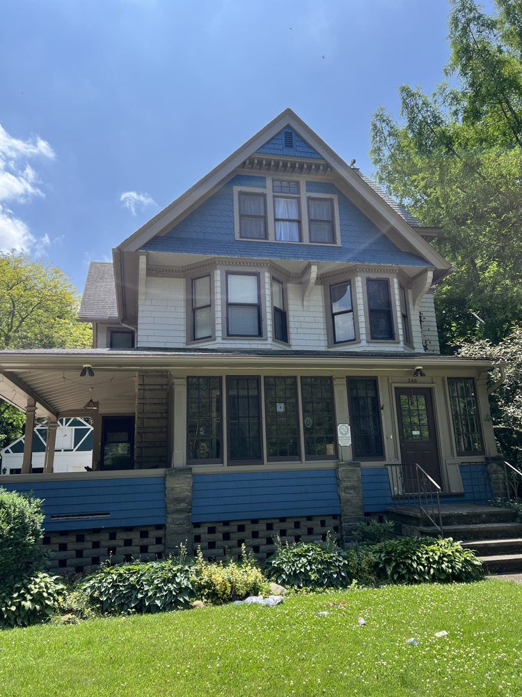 Two-story house with blue and white siding, large porch, and lawn.