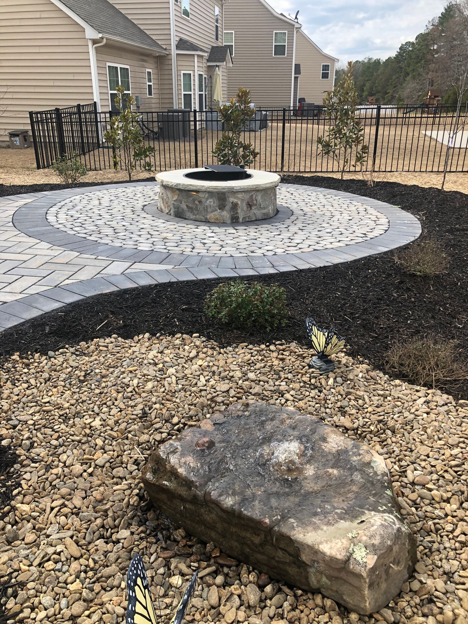 a fire pit is surrounded by gravel and a large rock .