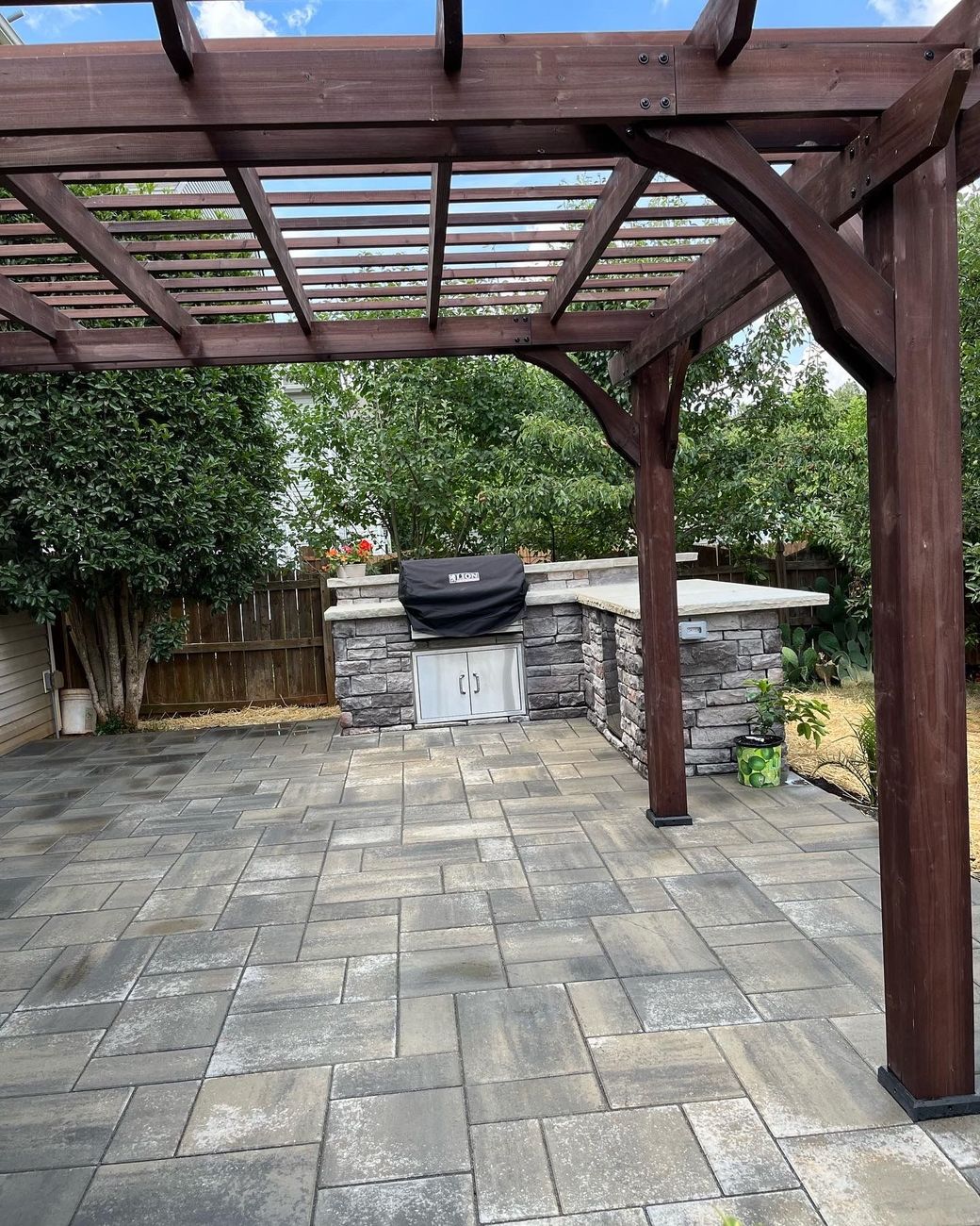 a wooden pergola over a patio with a grill underneath it .