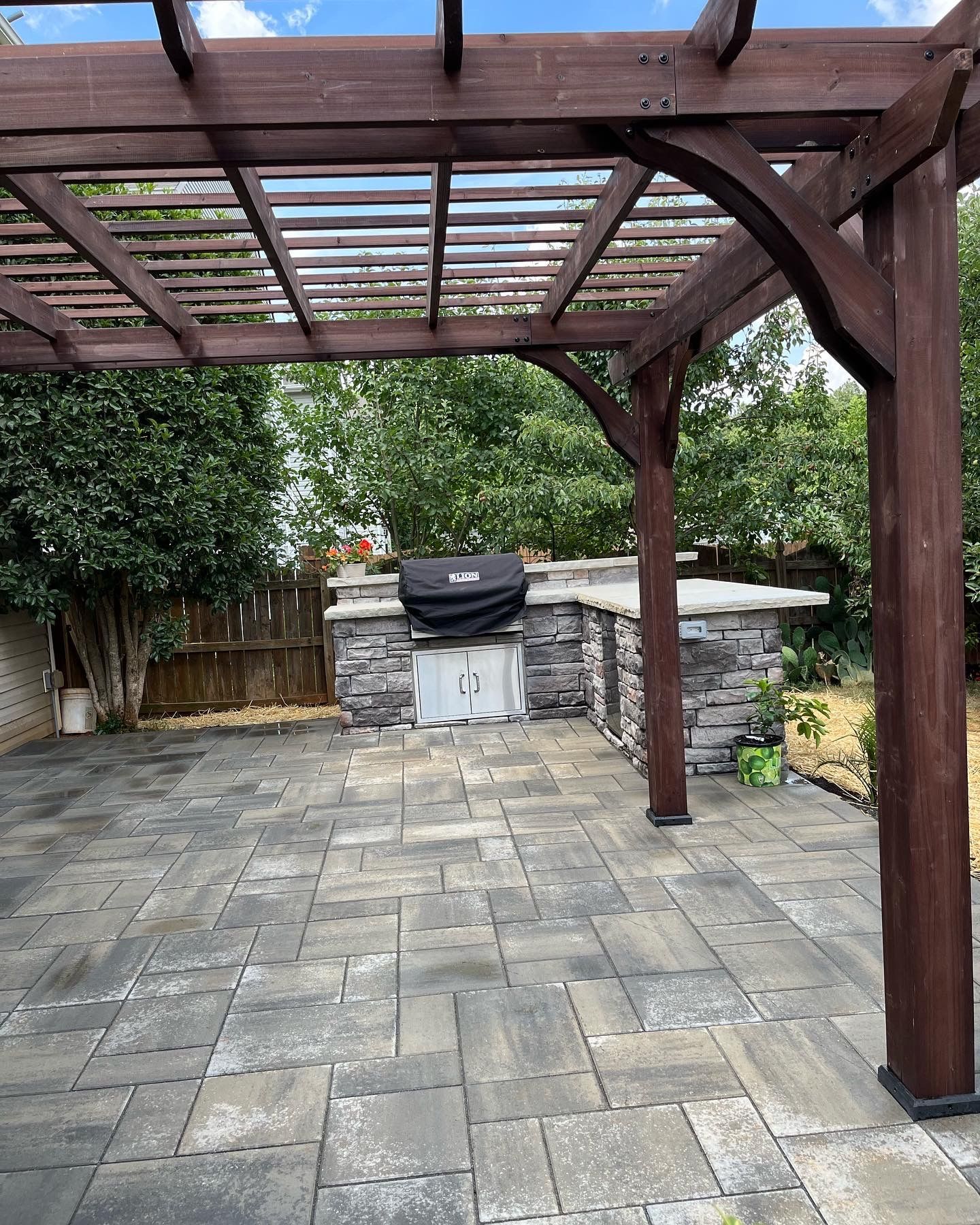 a wooden pergola over a patio with a grill underneath it .