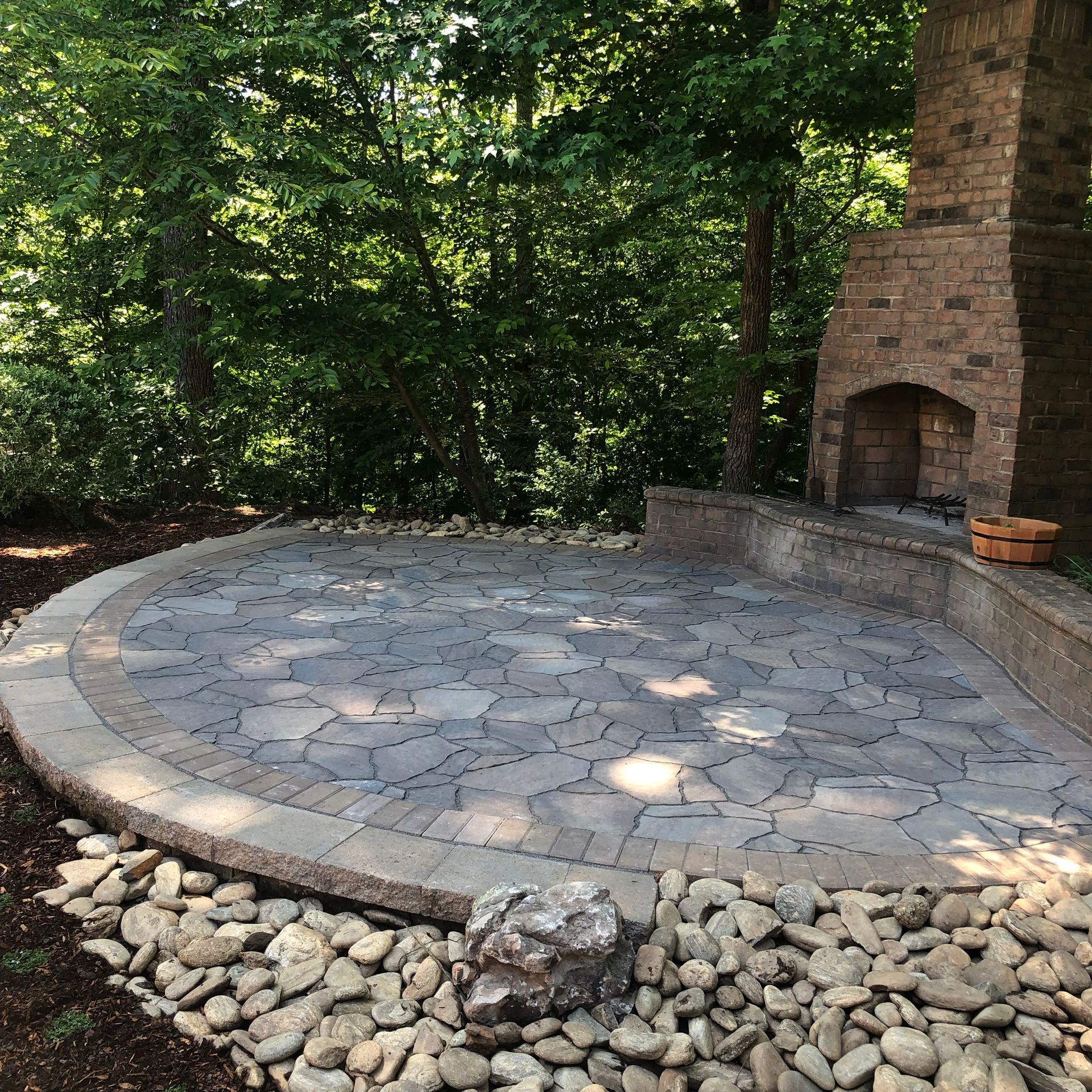 a stone patio with a fireplace in the background