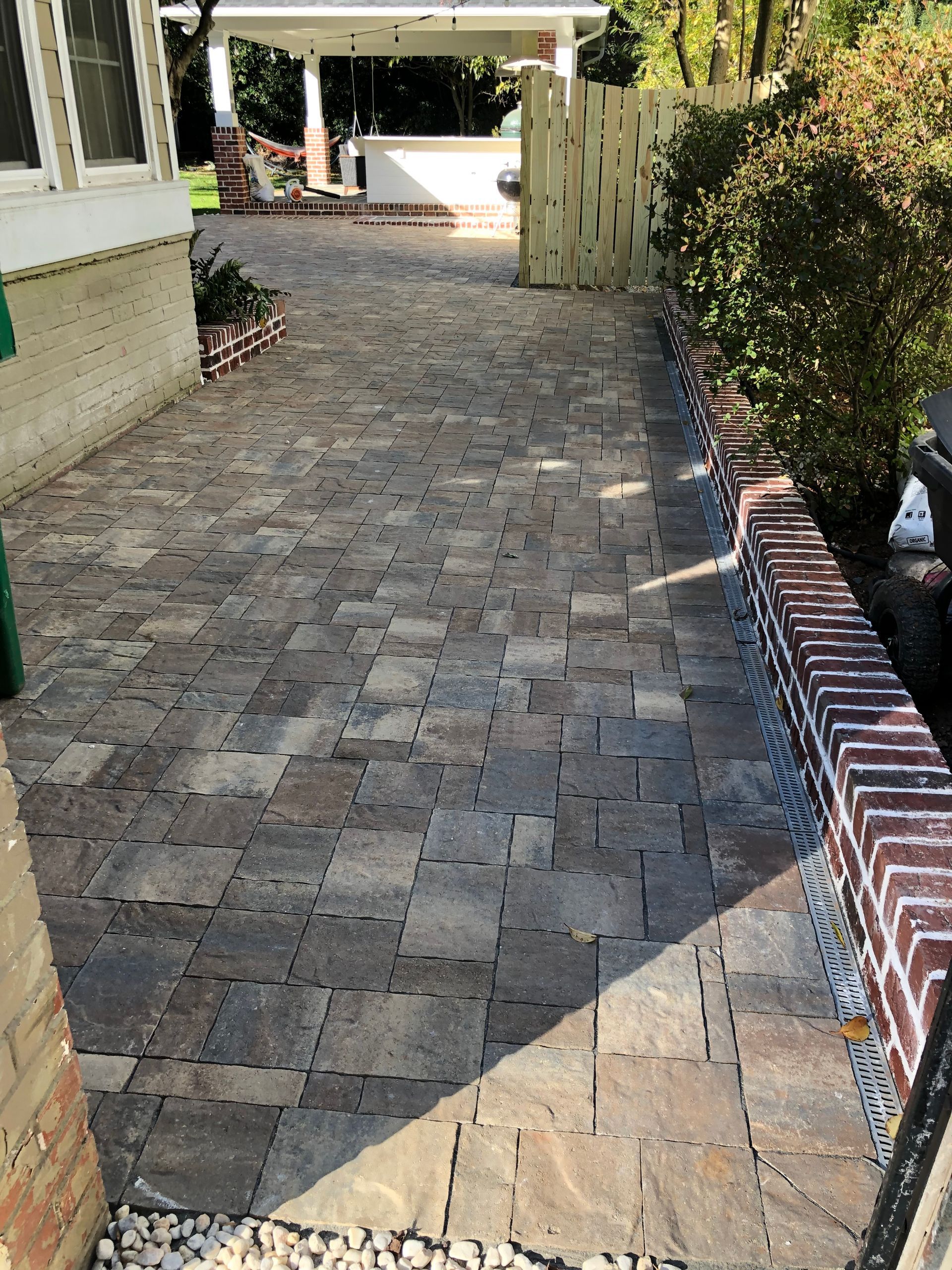 a brick driveway leading to a house with a brick wall .