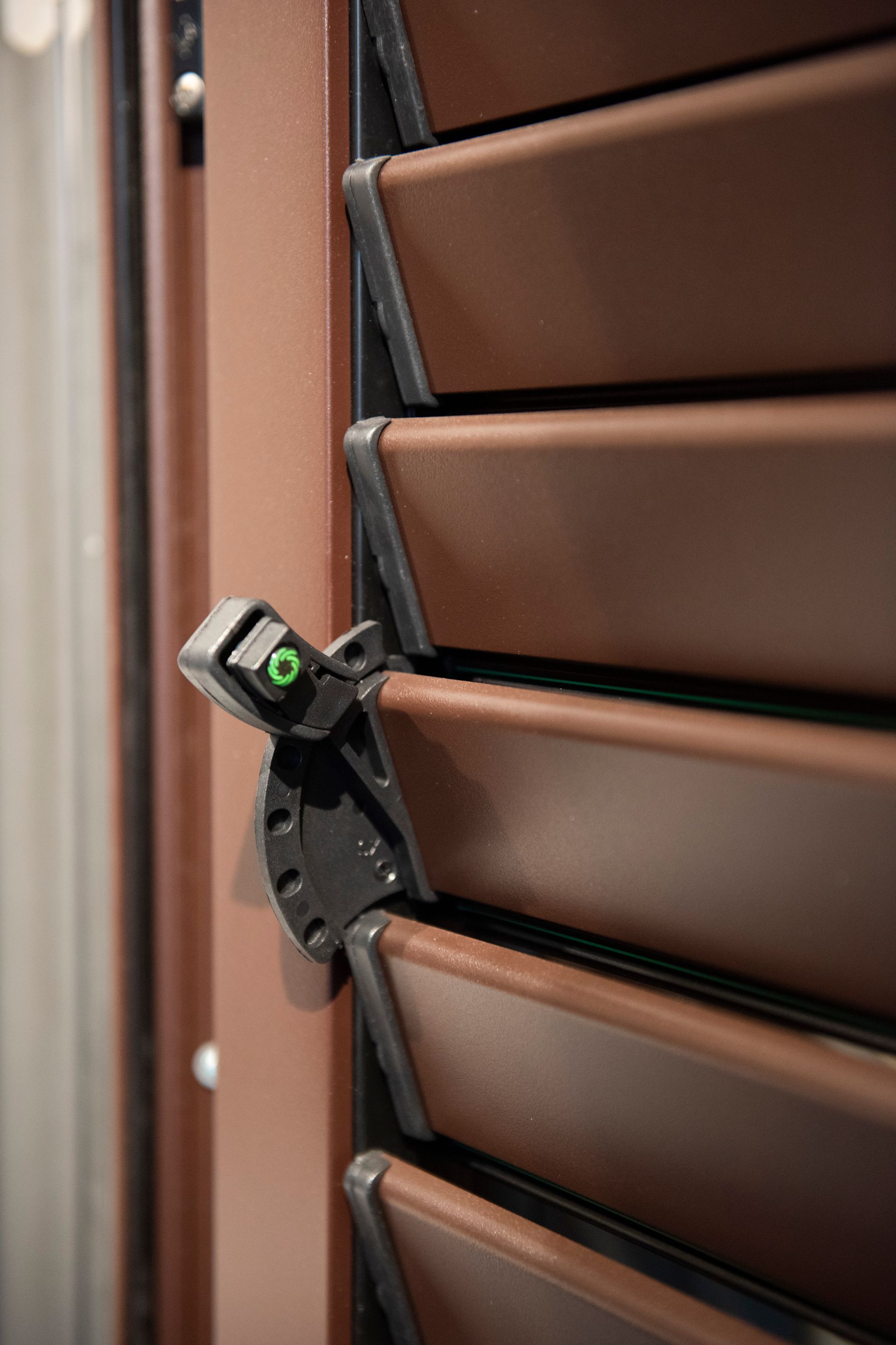 Otturatore marrone con meccanismo di azionamento nero, leggermente aperto.