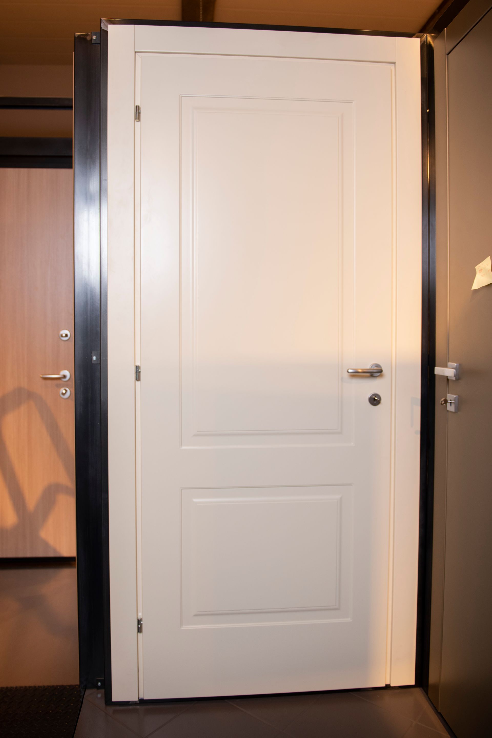 Porta interna bianca a due ante con ferramenta argentata. Altre porte sullo sfondo.