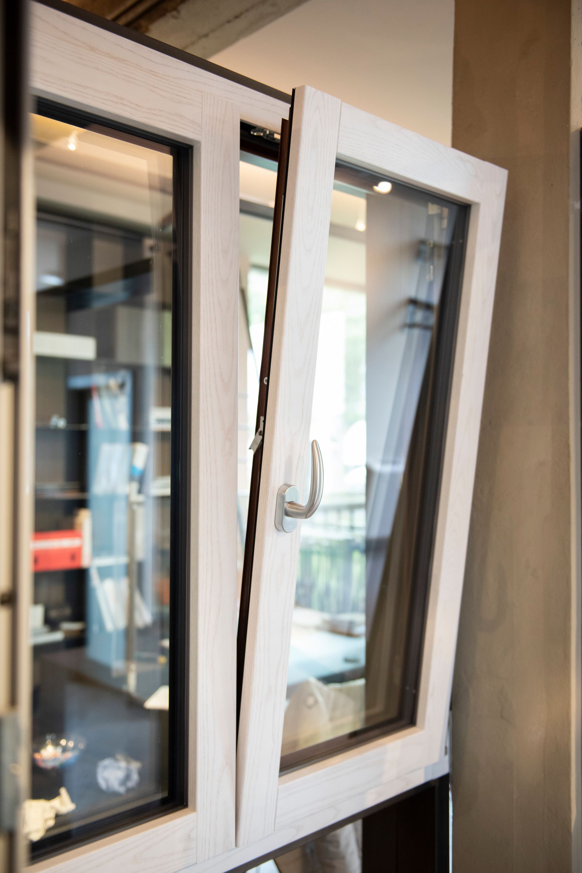 Finestra con cornice bianca, parzialmente aperta, che rivela la vista di una stanza e dell'esterno.