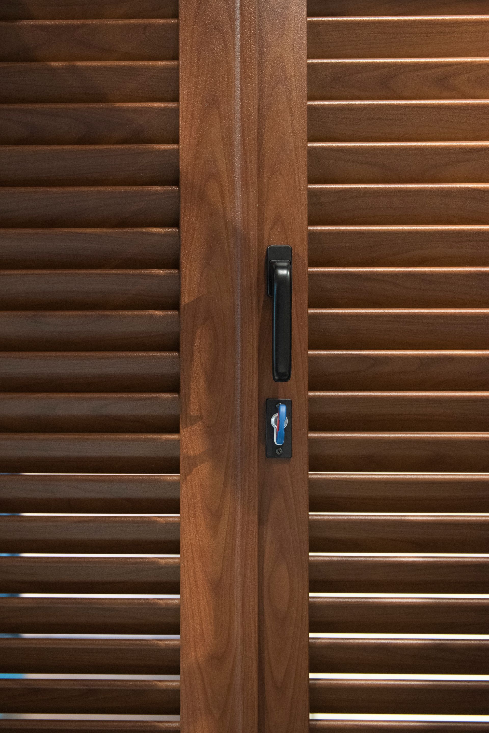 Porta a persiana in legno con maniglia e serratura scure.