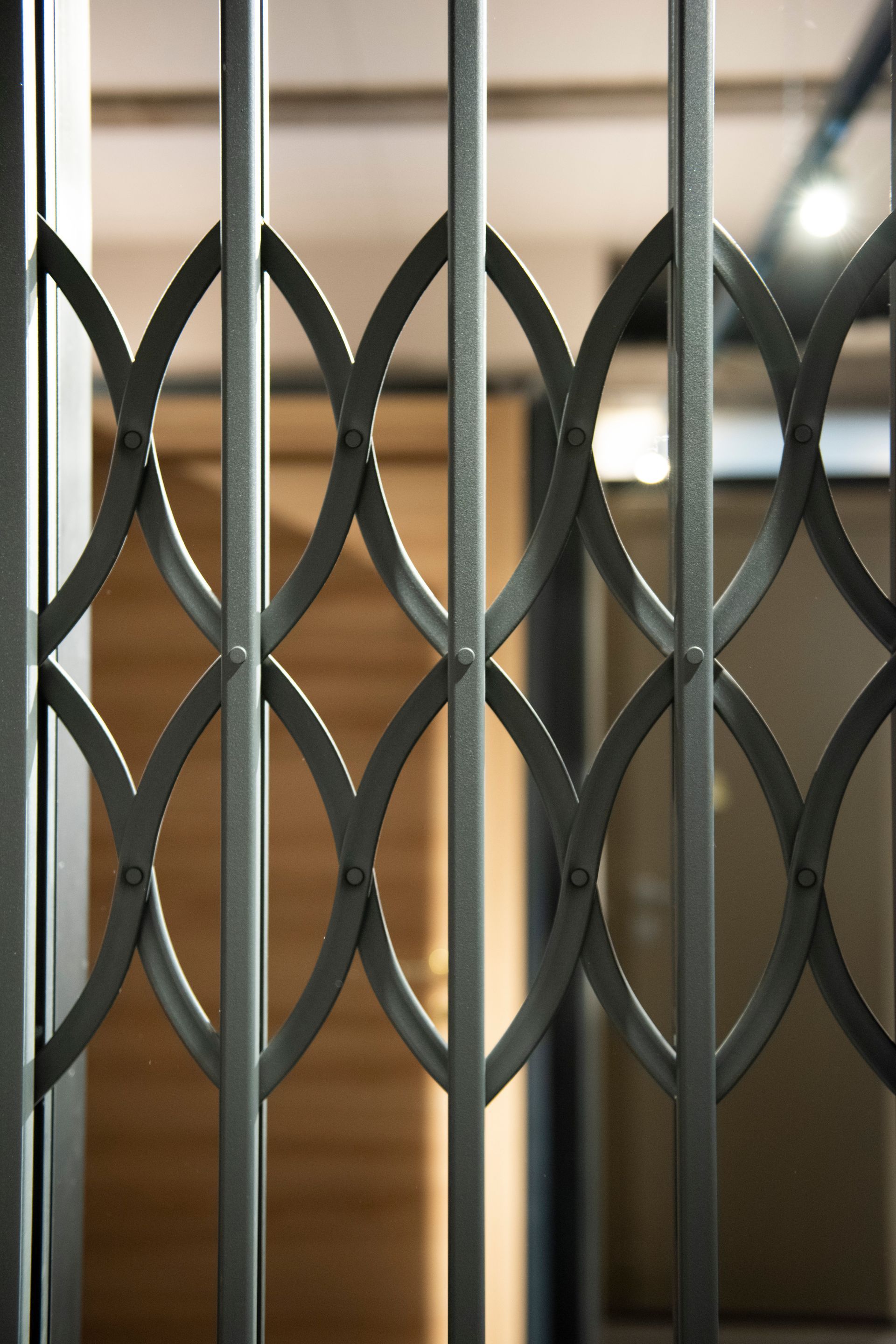 Cancello di sicurezza in metallo, grigio con motivo a rombi, che blocca parzialmente un corridoio.